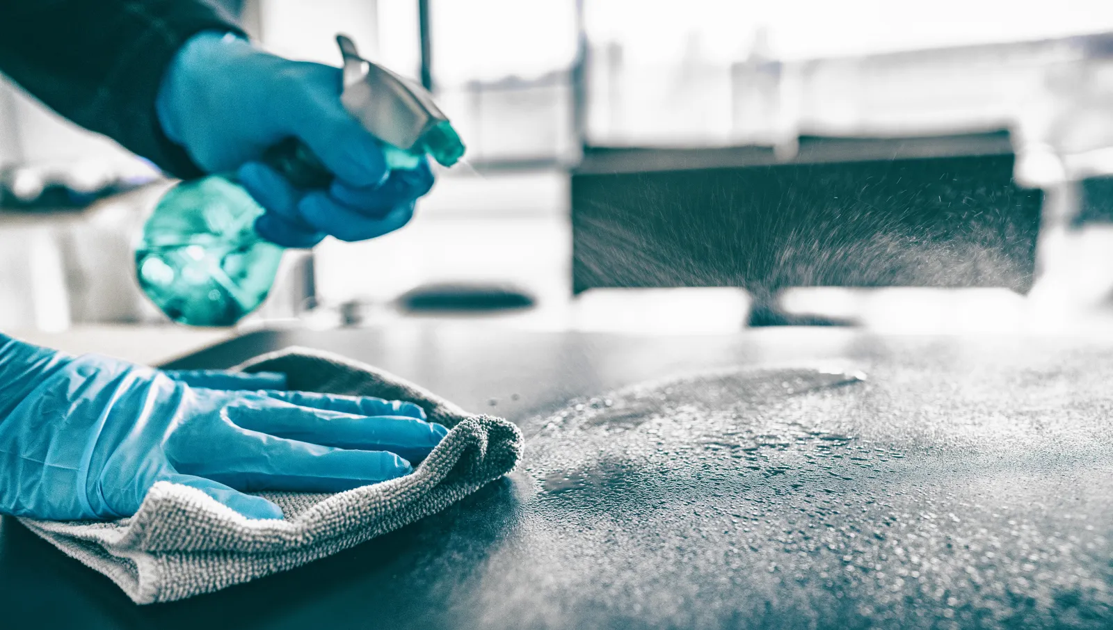 Flächendesinfektion mit Sprühflasche und Tuch in Schutzhandschuhen